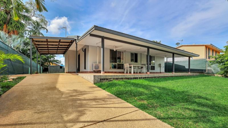 --Front of home with long tan driveway, grass, deck, carport.--