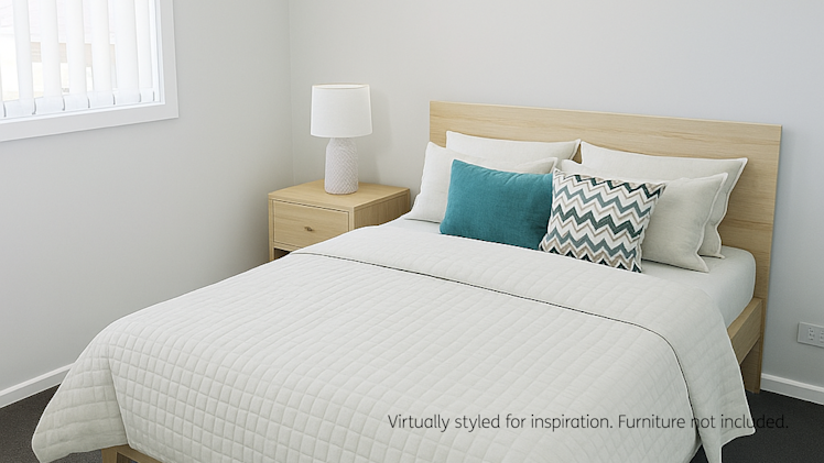 Virtually styled bedroom featuring a light wood bed with white quilted bedding, colorful cushions, and a matching bedside table with a lamp.