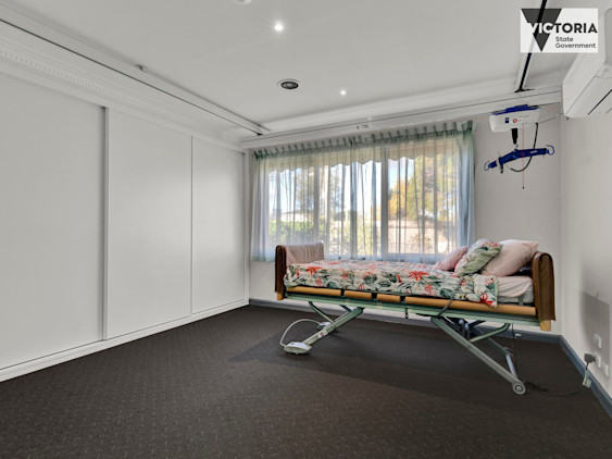 Bedroom with large window, ceiling hoist system, and adjustable care bed with floral bedding