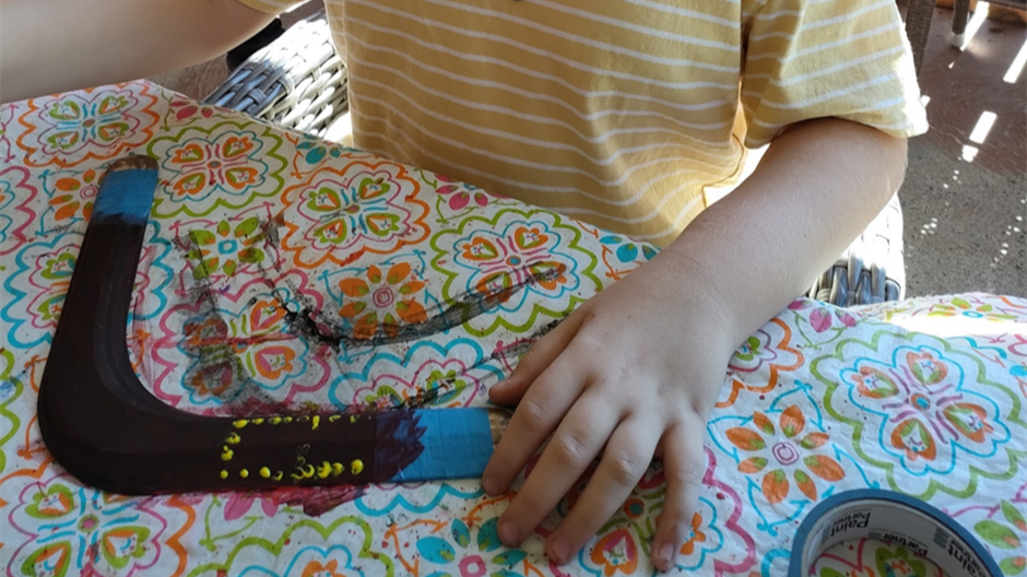 Close up of Ben's hands as he holds a boomerang that he has painted.