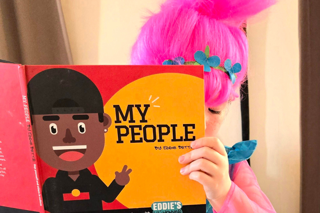 A young person in a costume reading a book.