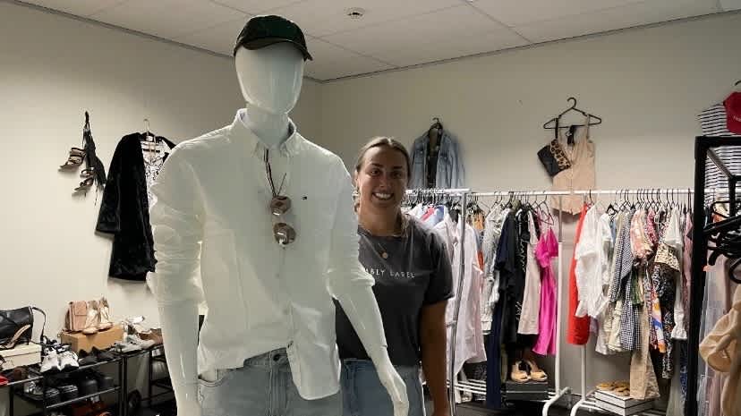 A woman standing next to a mannequin smiling at the camera.