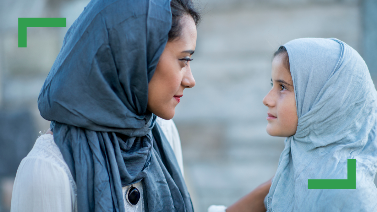 A woman wearing a blue Hijab next to her daughter wearing a light blue Hijab.