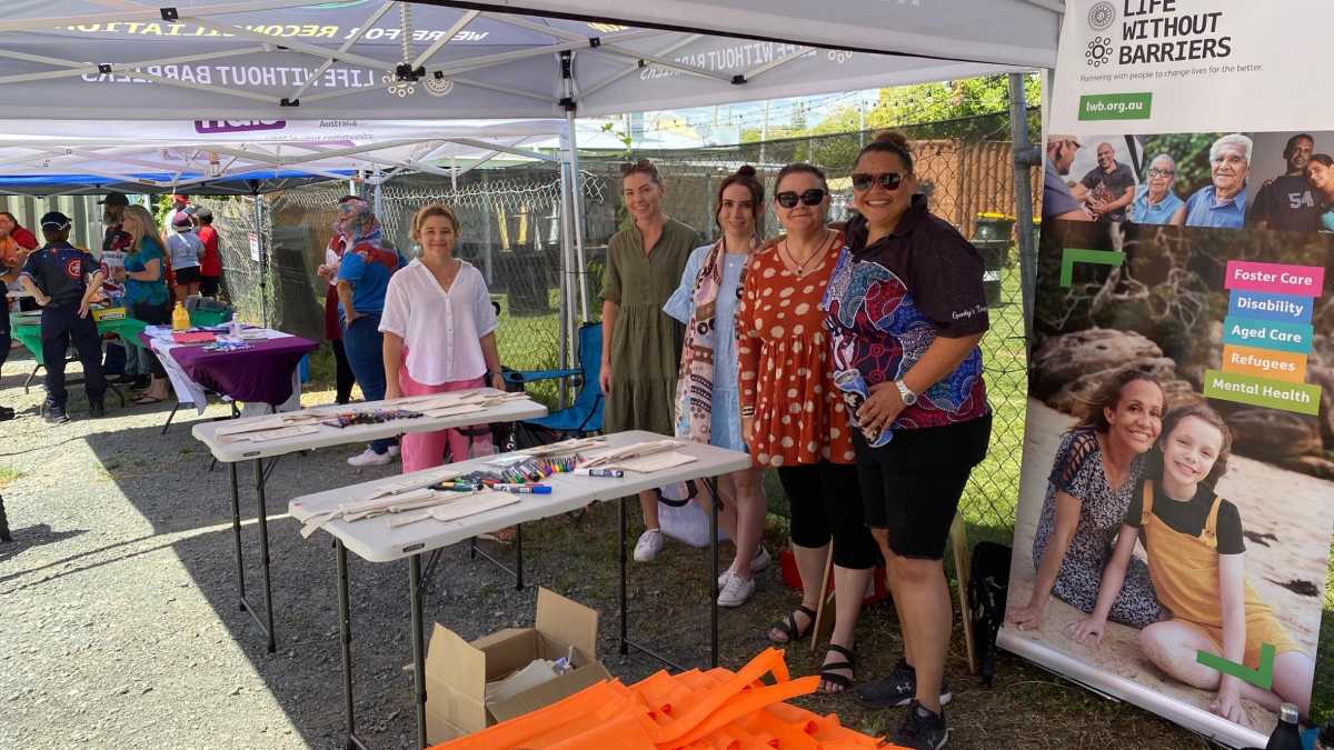 Life Without Barriers staff members standing together at a stall at the Kurbingui Back to School Day.