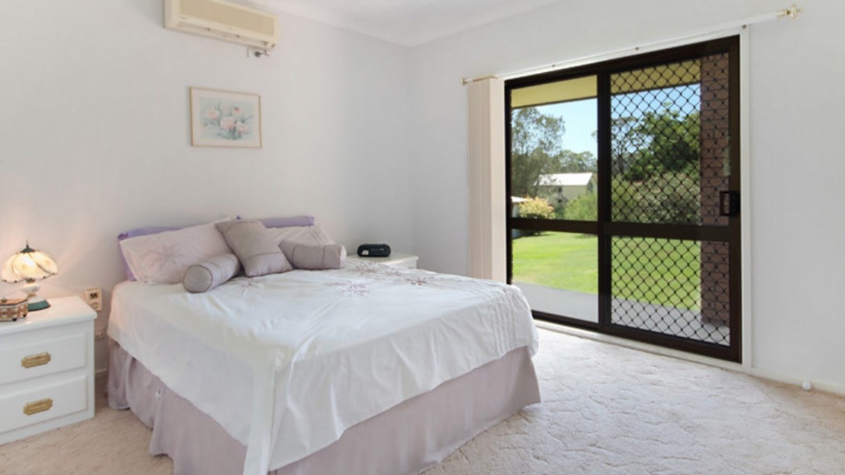 Bright bedroom with a double bed, ceiling fan, white furniture, and glass sliding door opening to the garden.