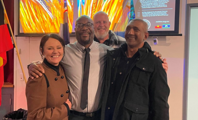 Four people smiling at the camera at a Toowoomba NAIDOC Event.