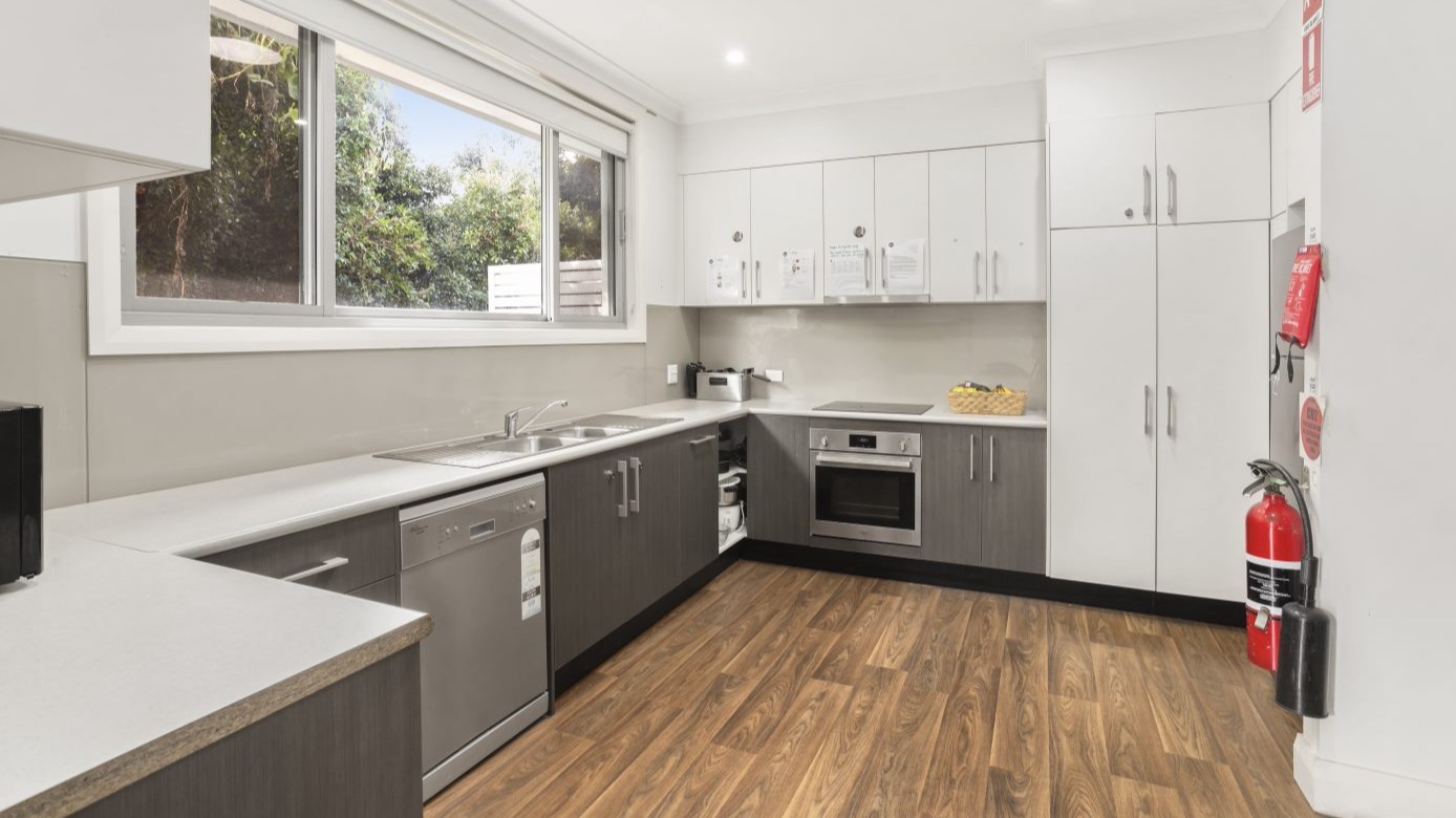 --Kitchen with wooden floor boards, grey cabinets, a dishwasher, oven and induction stove.--