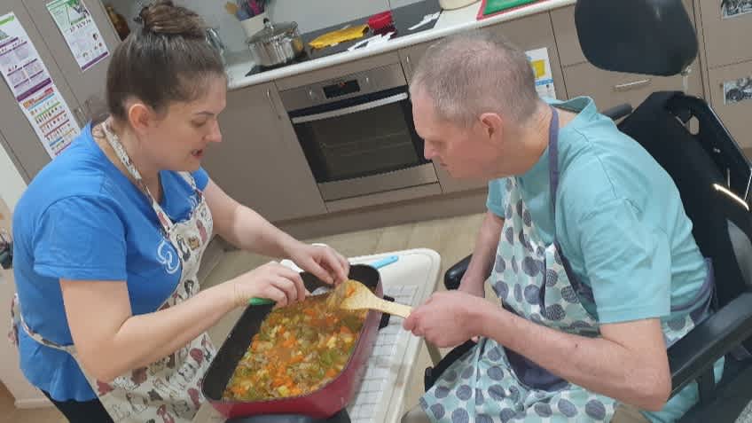 Bruce learning to cook with a support worker.