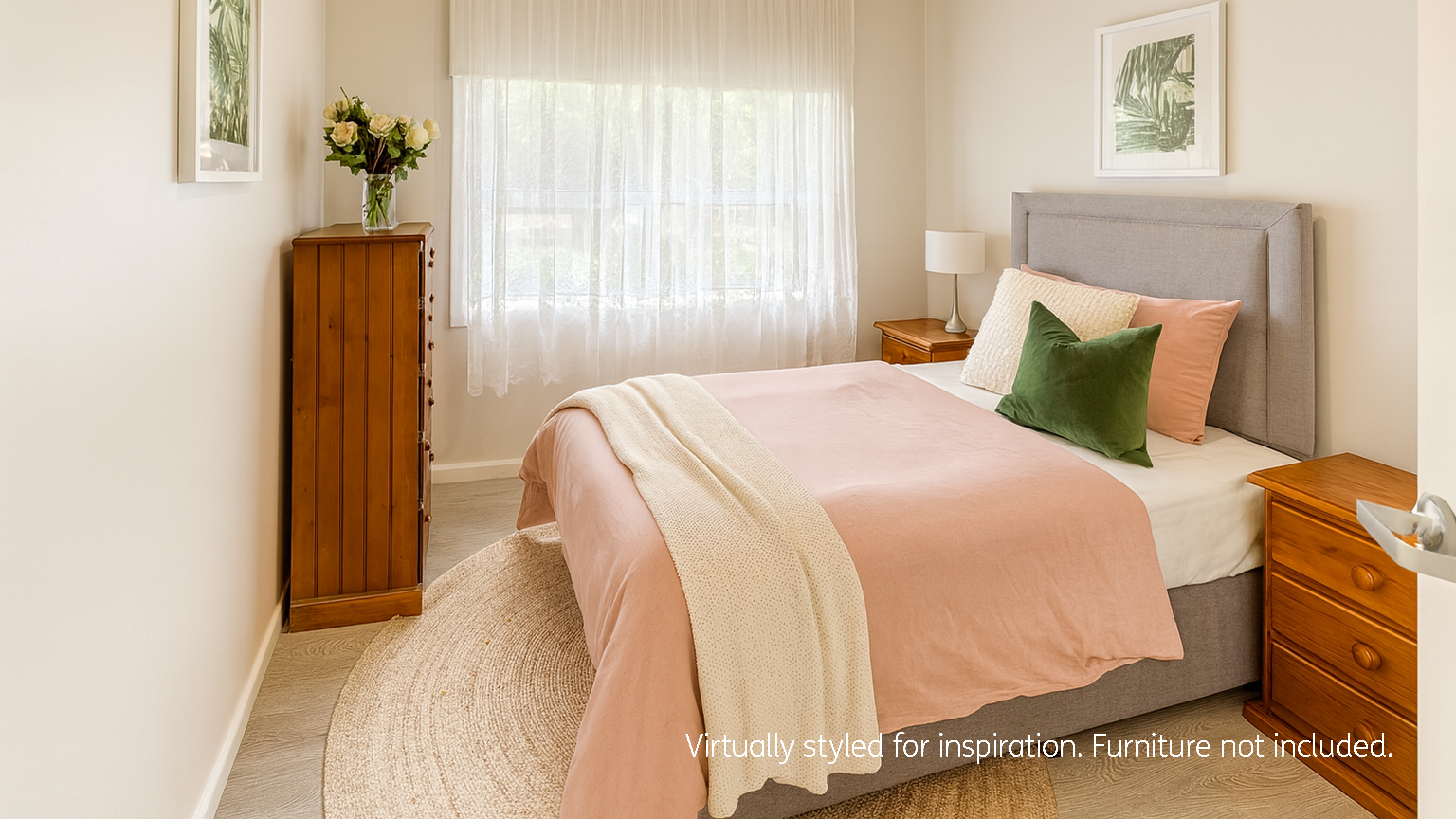 A bright, modern bedroom featuring a grey upholstered bed with blush bedding and green accent cushions, wooden bedside tables, a tall dresser, and soft natural light filtering through lace curtains.