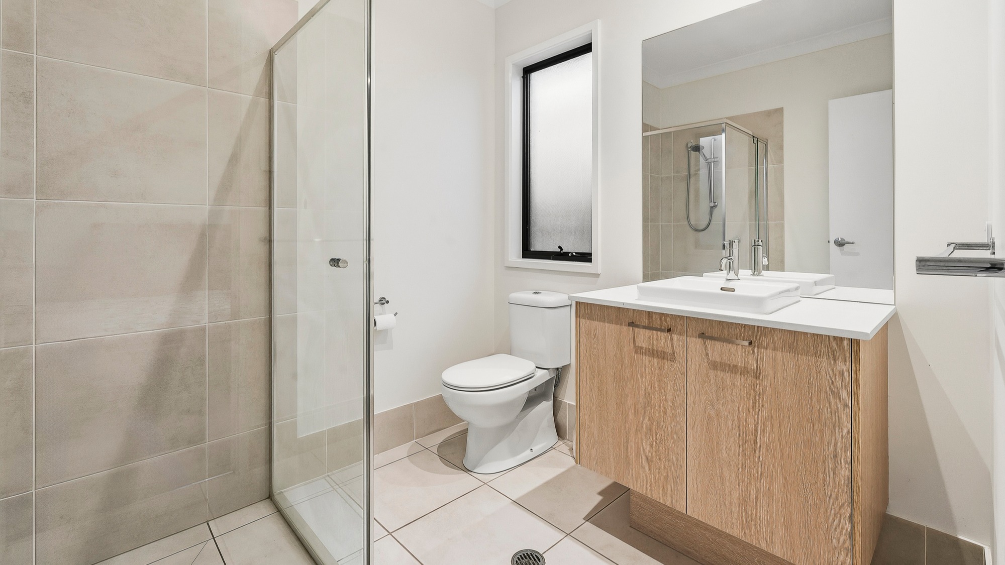 ensuite bathroom with walk-in shower, toilet and vanity with mirror.