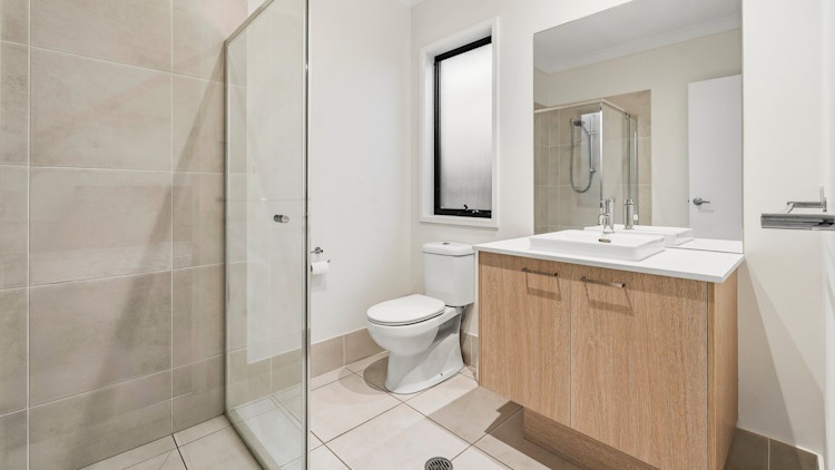 ensuite bathroom with walk-in shower, toilet and vanity with mirror.