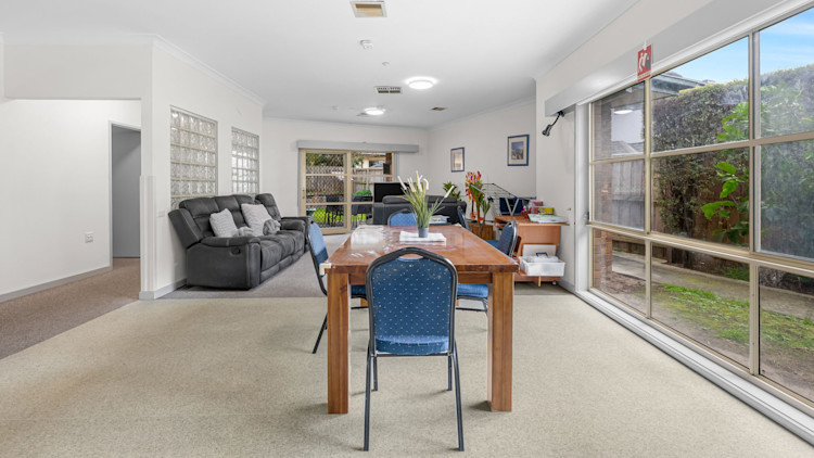 Bright communal area with dining table, sofa, and sliding door to garden.