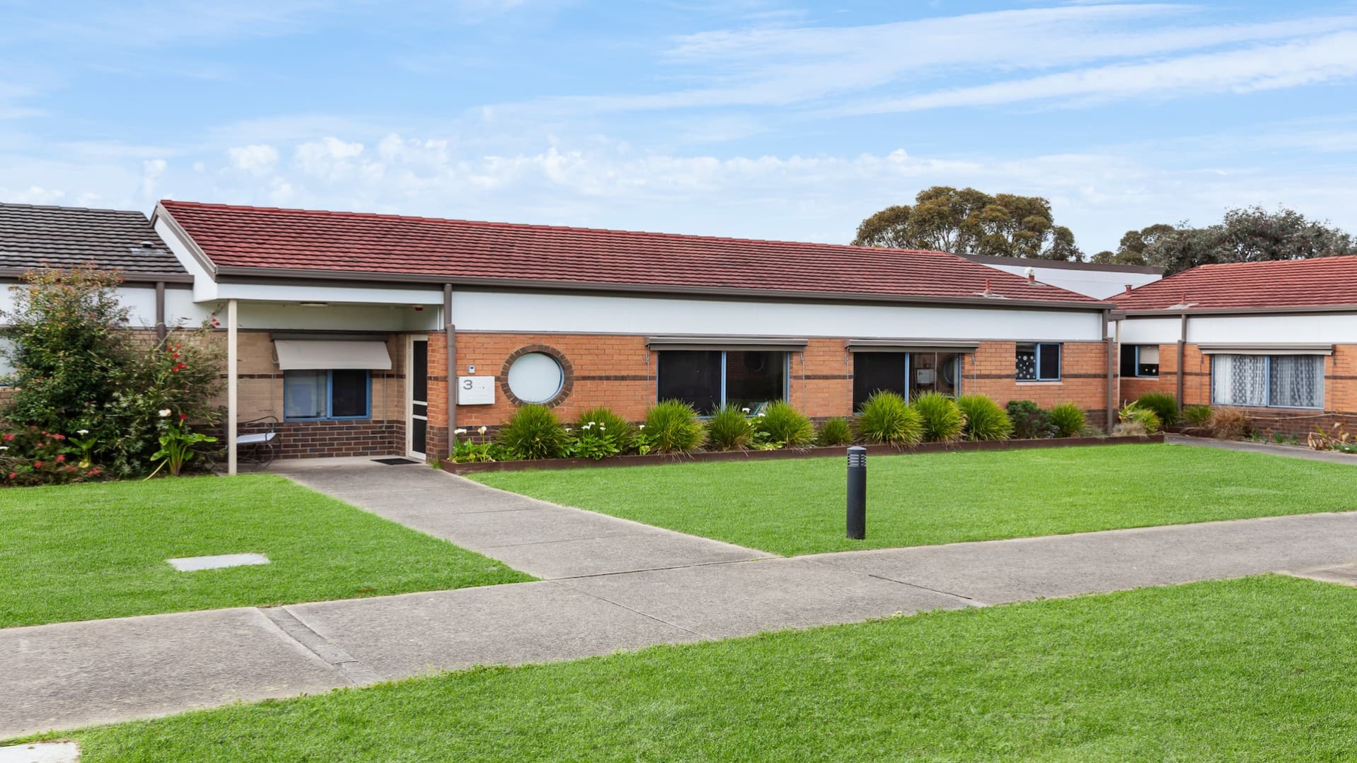 front exterior view of single storey red brick house with wide entrance pathway