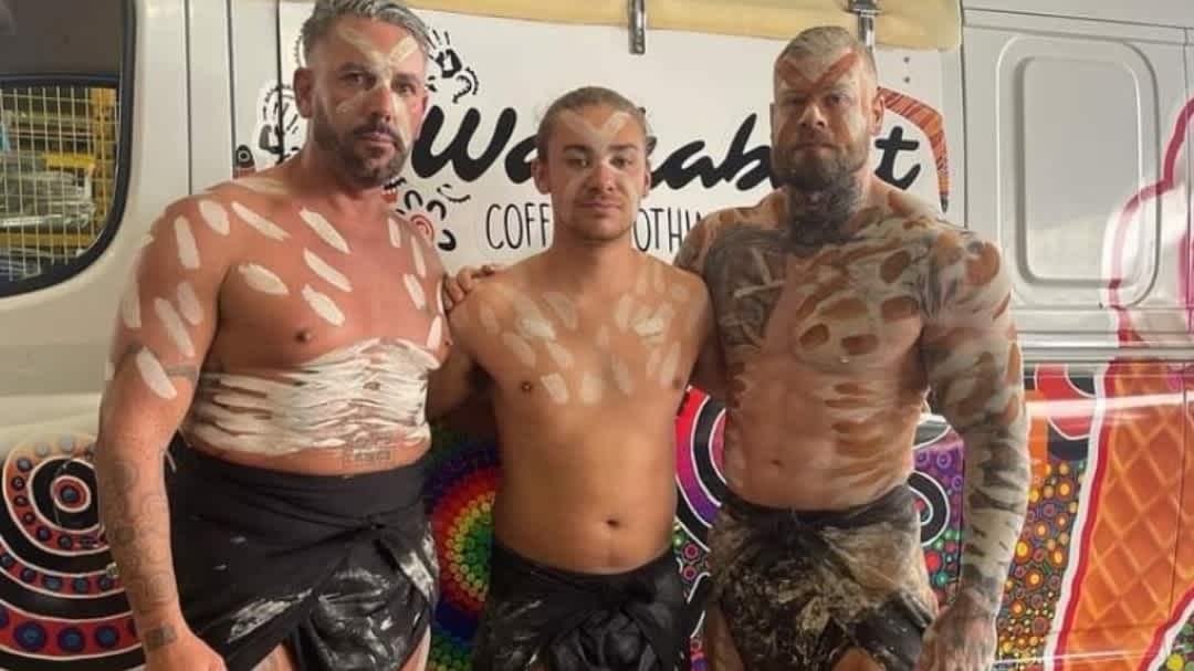 Luke Barnes and two Aboriginal men stand together wearing white body paint.