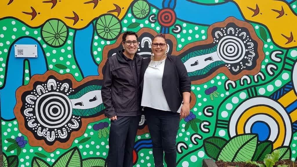 Silvia with her mentor and co-artist Stephen Hogarth in front of their mural named A Place Where We Gather.