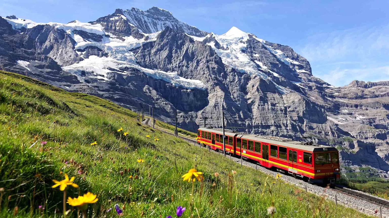 A tourist train travels on Jungfrau Railway from Jungfraujoch Top of Europe to Kleine Scheidegg