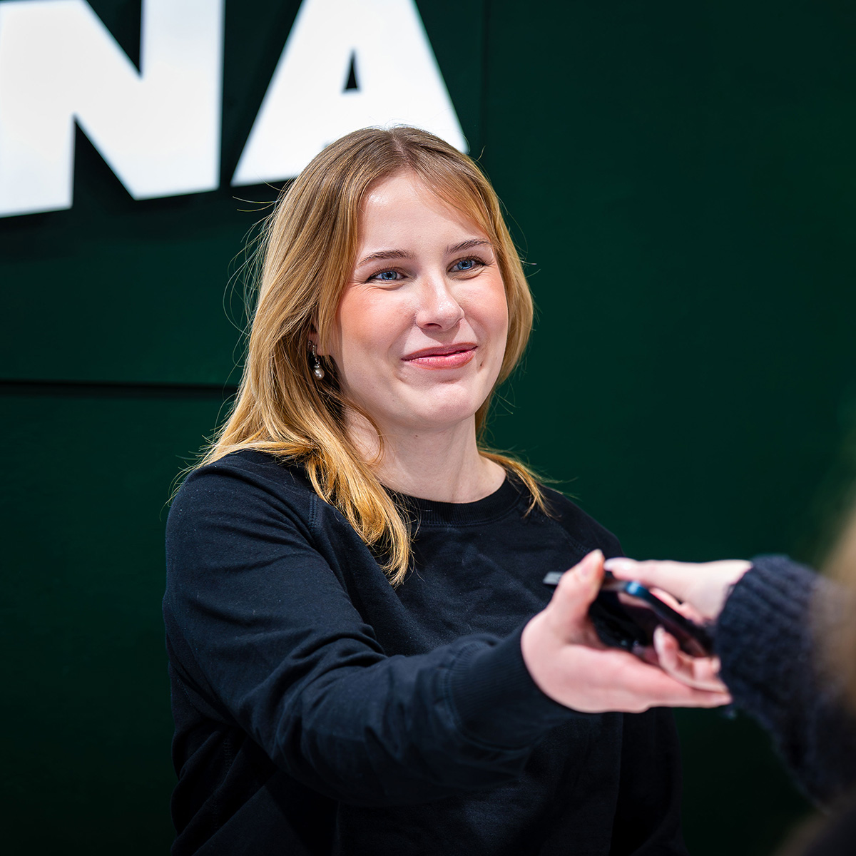 Myyjä ojentaa korjatun puhelimen asiakkaalle