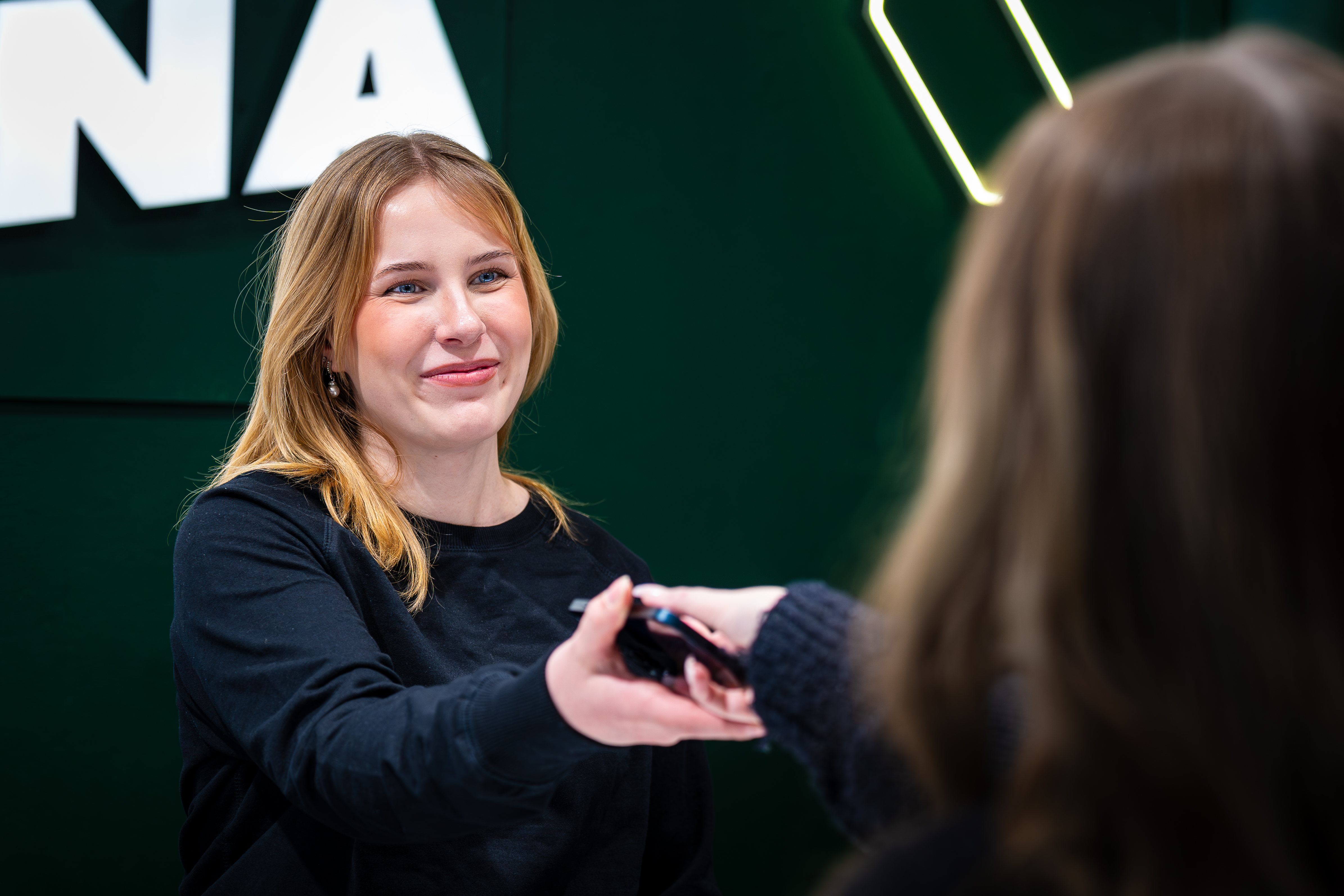Myyjä ojentaa korjatun puhelimen asiakkaalle