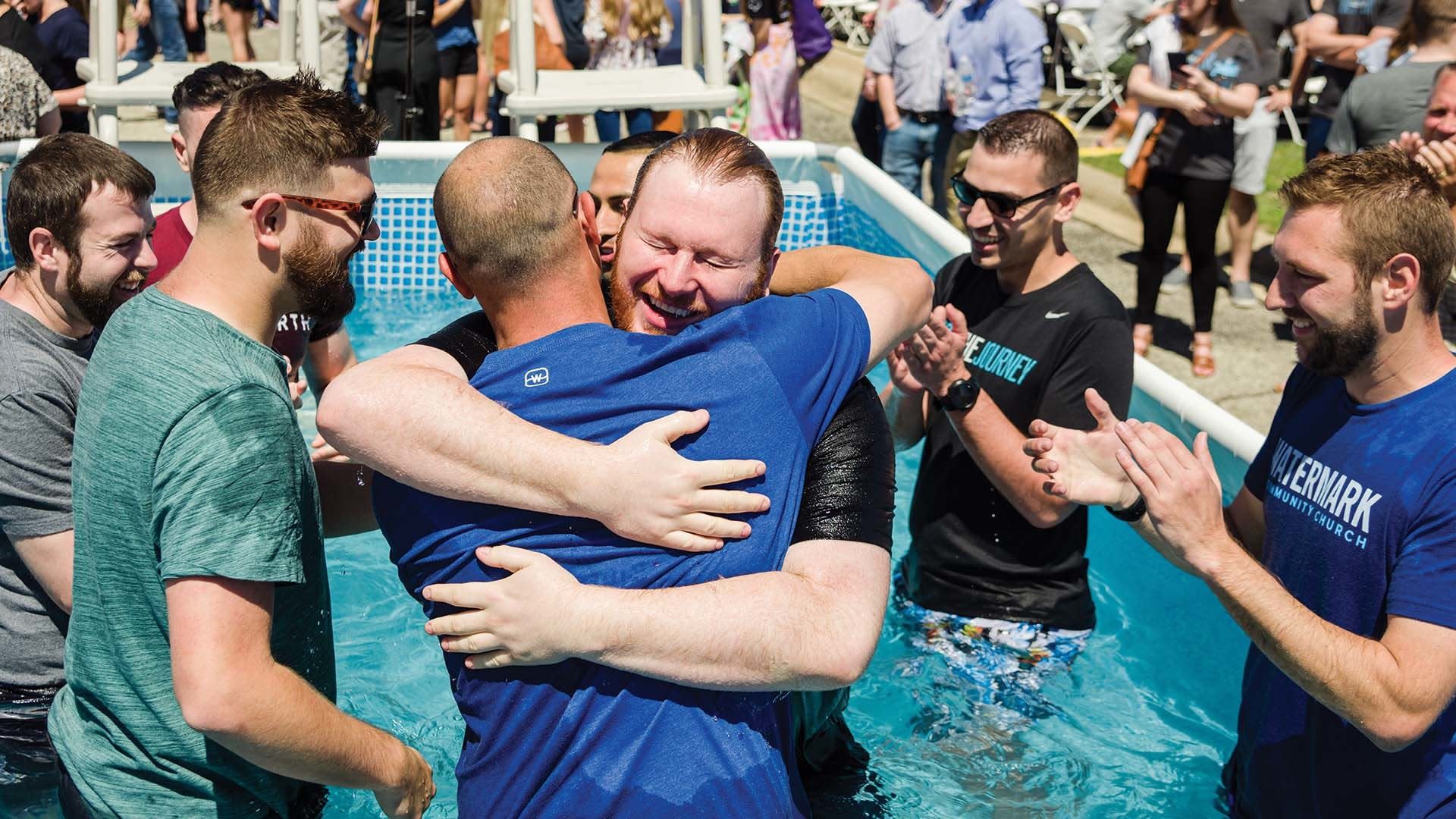 Friends hugging in baptismal pool