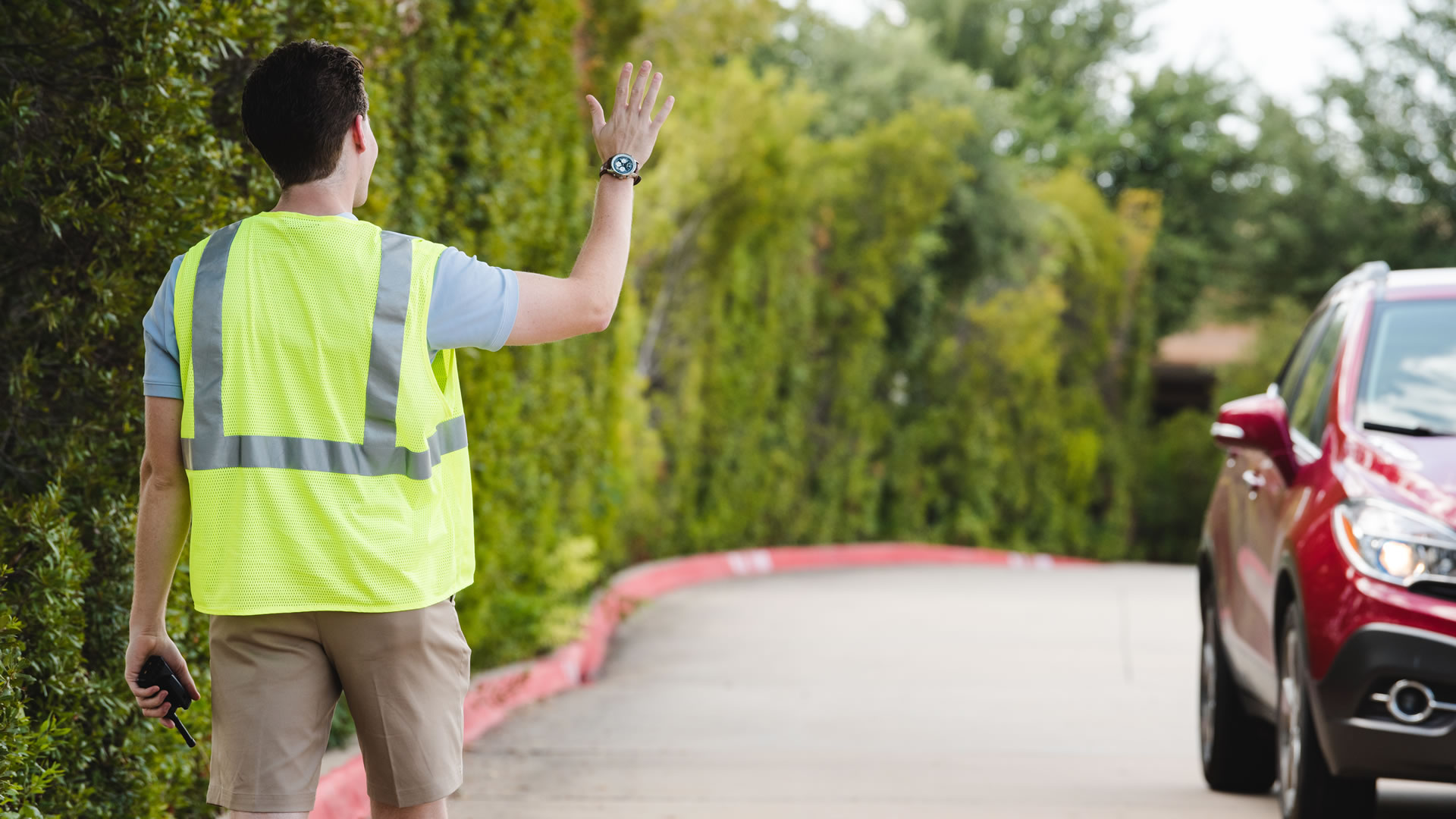Watermark parking team volunteer welcoming cars in parking lot.