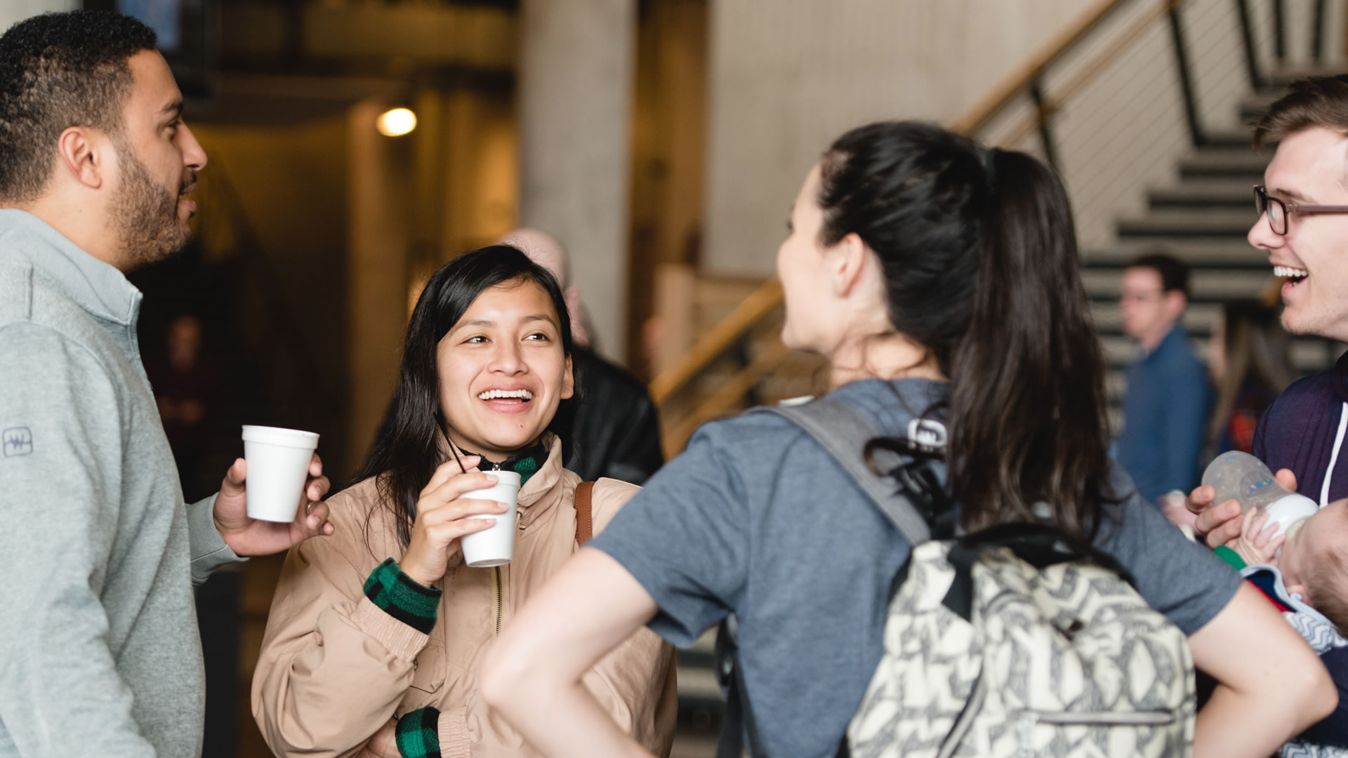 Smiling group of people drinking coffee outside the Auditorium of Watermark Community Church in Dallas, Texas. 