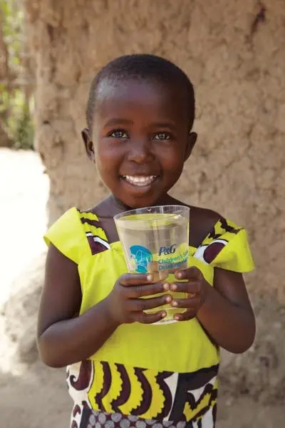 Niña feliz con vaso de agua en la mano.