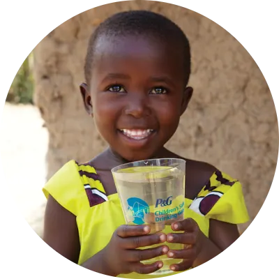 Niña feliz con vaso de agua en la mano.