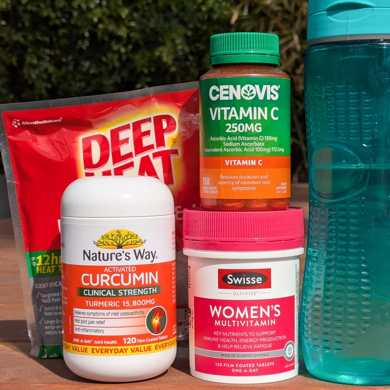 Health products including Deep Heat, Cenovis Vitamin C, Nature's Way Curcumin, and Swisse Women's Multivitamin beside a teal water bottle.