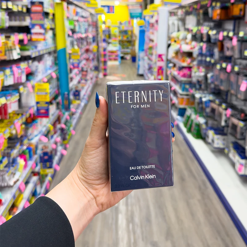 Hand holding a dark box of Calvin Klein Eternity for Men cologne against a bright background.
