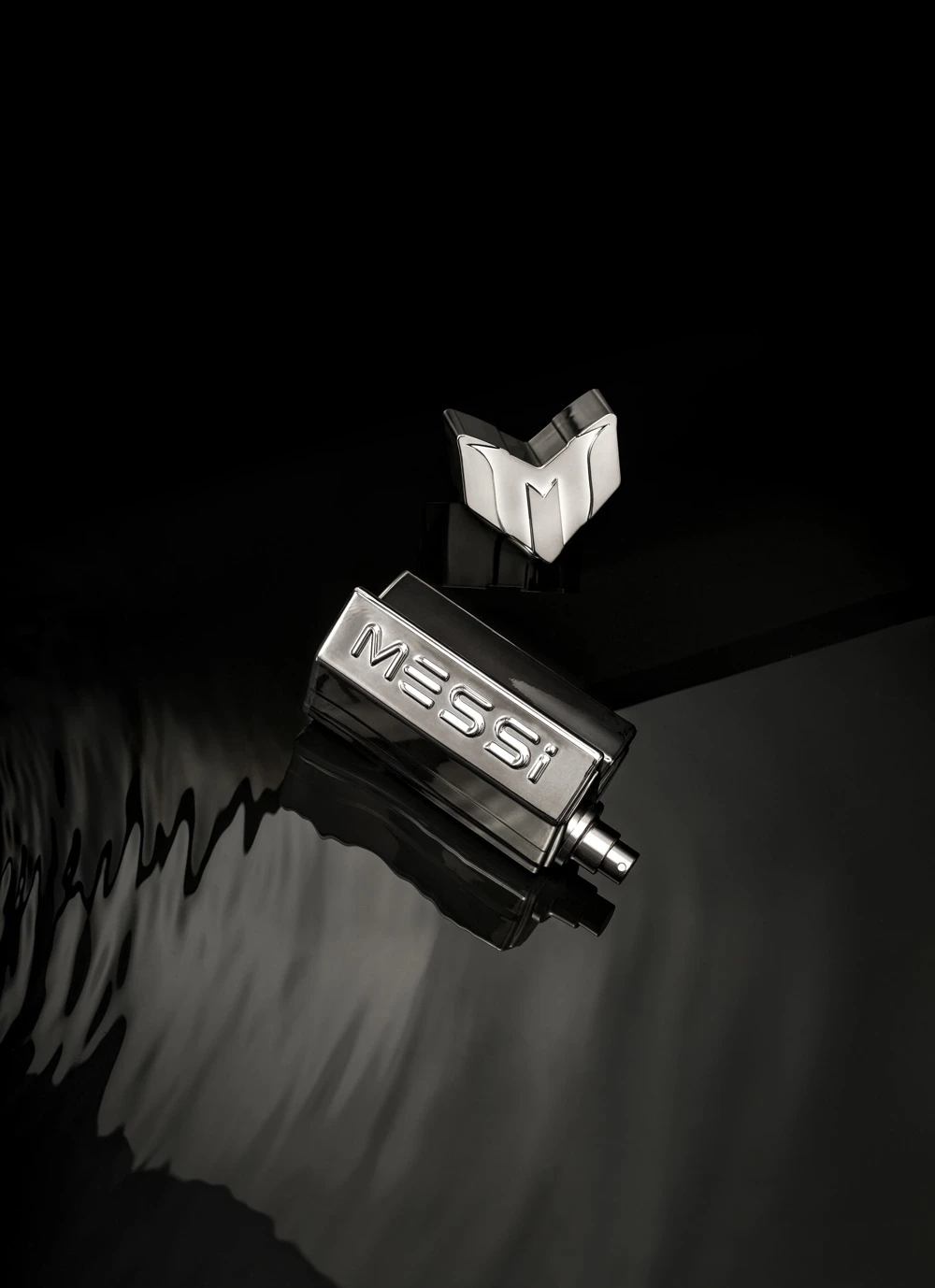 A black and silver Messi fragrance bottle photographed face up against a dark background with dramatic shadows
