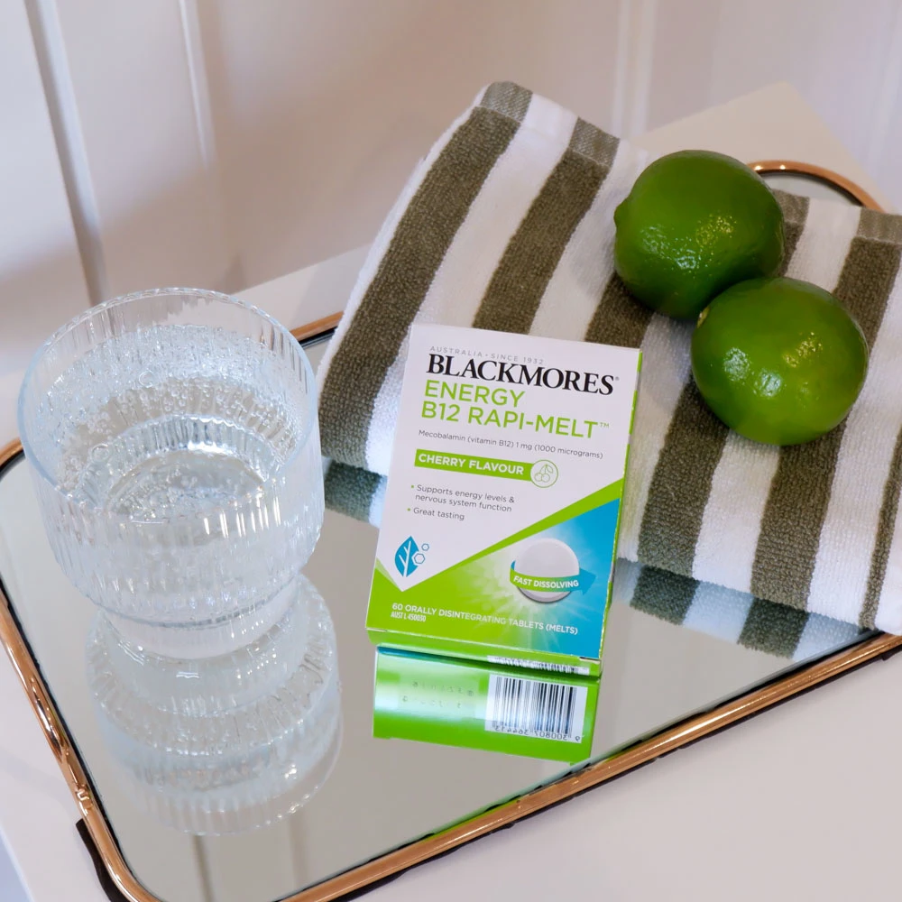 Blackmores Energy B12 Rapi-Melts on a mirror with fruit and a glass of fizzy water
