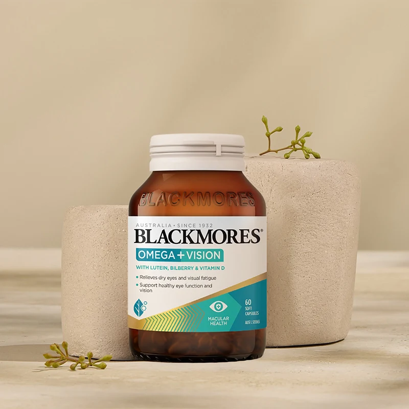 Blackmores Omega+Vision supplement bottle displayed with concrete planters and small green sprouts on beige background.