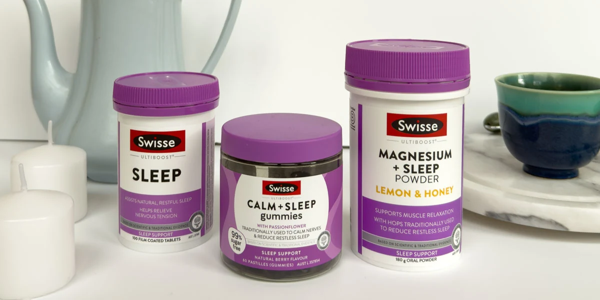Swisse sleep supplements in purple packaging displayed with white candles and a vintage gray teapot on marble surface