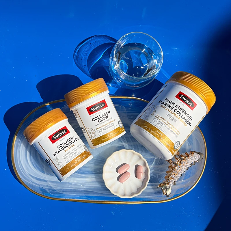 Three Swisse collagen supplement containers with gold lids and pink tablets scattered on bright blue background