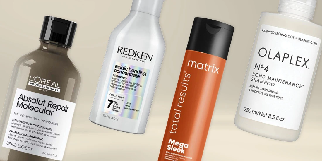 Four professional hair care shampoo bottles from L'Oreal, Redken, Matrix, and Olaplex brands arranged on beige background