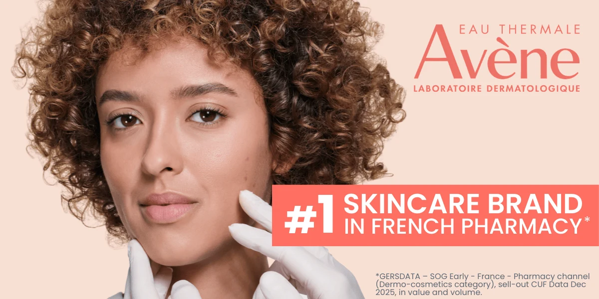 Close-up of curly-haired model with Avène Ultra Light Texture SPF50+ sunscreen product in orange packaging