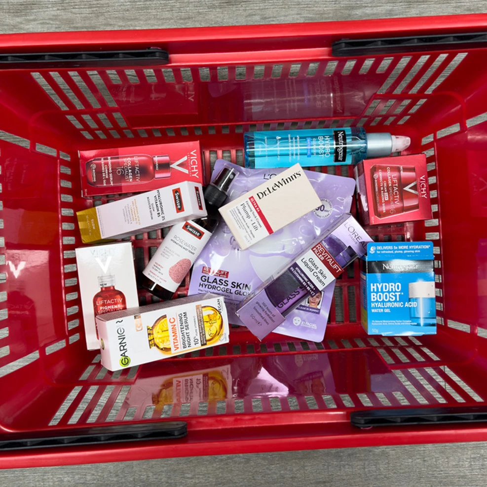 Red shopping basket filled with various skincare products including Vichy, Neutrogena, Garnier, L'Oreal, and Dr. LeWinn's.