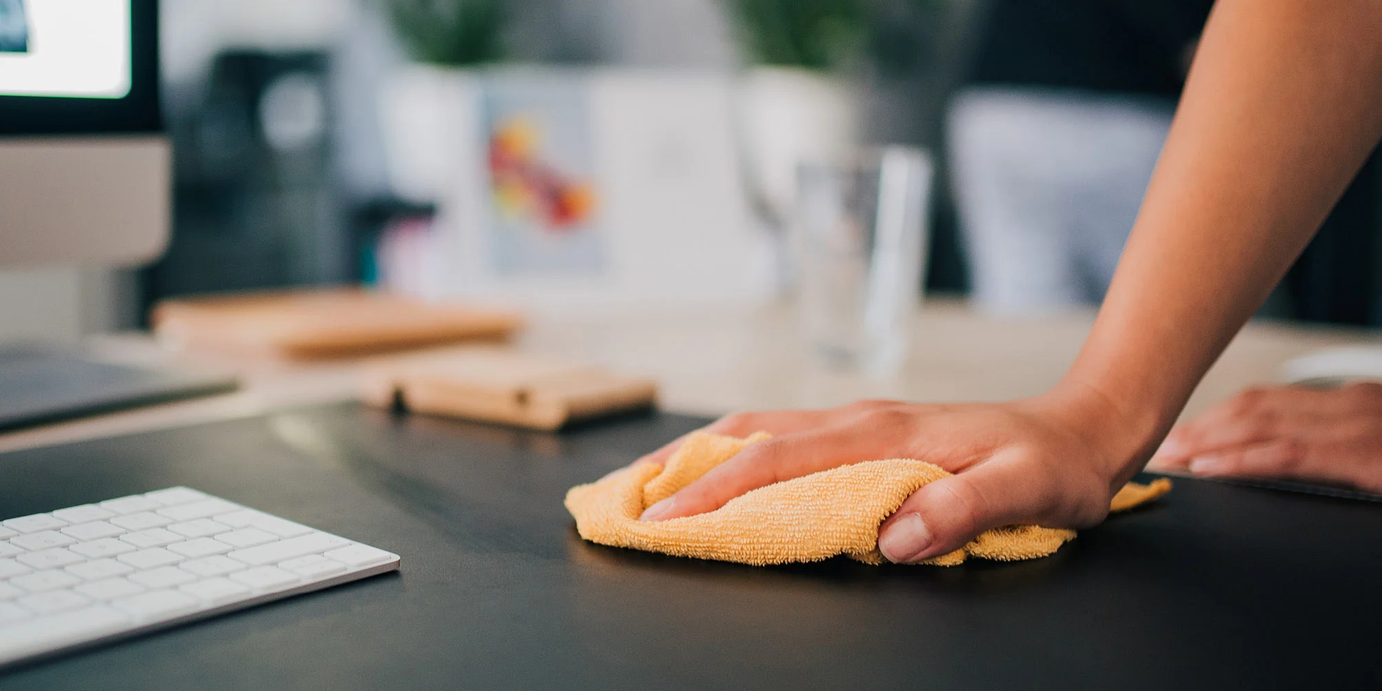 Hand cleaning a desktop with a cloth