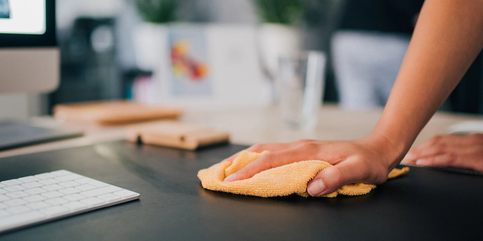 Hand cleaning a desktop with a cloth