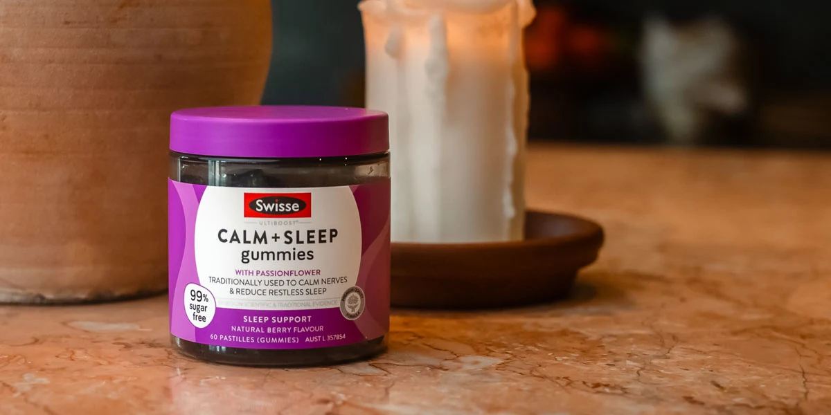 Swisse Calm + Sleep gummies on yellow fabric and behind a red wall