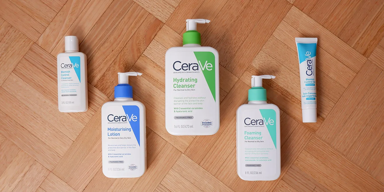 Collection of CeraVe skincare products including cleansers and moisturizing lotions arranged on wooden parquet flooring.