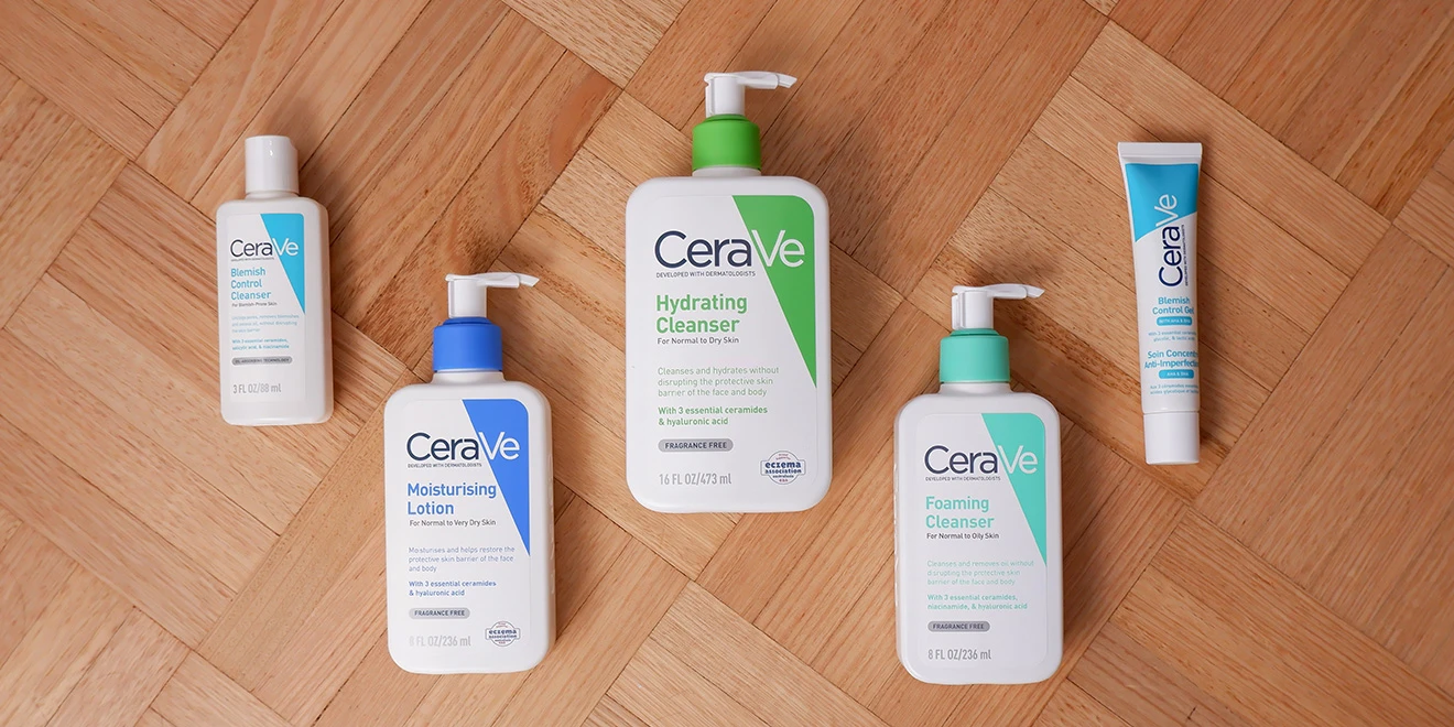 Collection of CeraVe skincare products including cleansers and moisturizing lotions arranged on wooden parquet flooring.