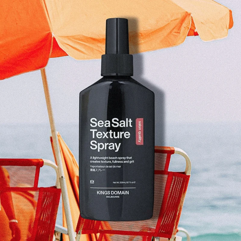 Two sea salt hair texture spray bottles on glass shelf - turquoise Toni&Guy and black Kings Domain products