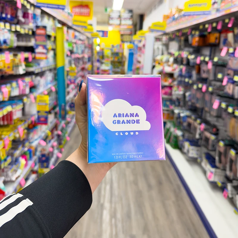 Hand holding Ariana Grande Cloud perfume box in retail store aisle