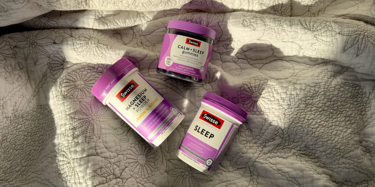 Seisse Magnesium + Sleep, Calm + Sleep gummies and Sleep products on a floral bed quilt in warm lighting