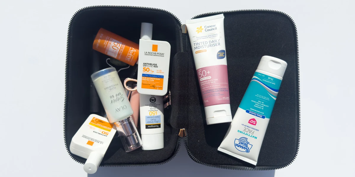 Open black toiletry bag containing multiple SPF sunscreen products including La Roche-Posay, Olay, Neutrogena, Cancer Council, and Banana Boat.