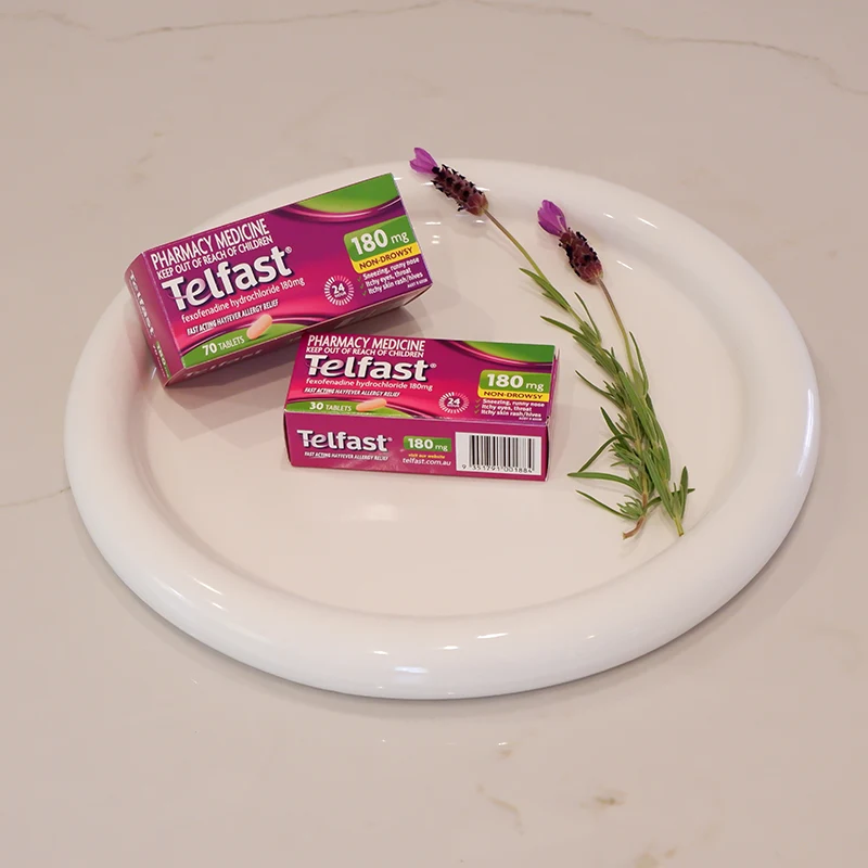 Two boxes of Telfast 180mg allergy medication on a white plate with purple lavender sprigs.