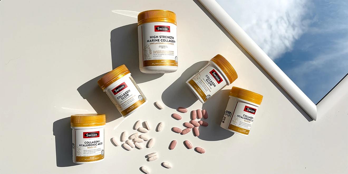 Swisse collagen supplement bottles with gold caps arranged diagonally with scattered pink tablets, casting dramatic shadows on white surface