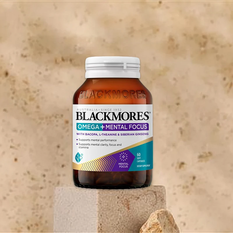 Brown glass bottle of Blackmores Omega + Mental Focus supplement displayed on concrete pedestal against beige background.