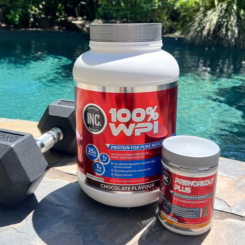 Protein powder containers and dumbbell displayed by turquoise pool, featuring INC brand supplements in chocolate and mango flavors.